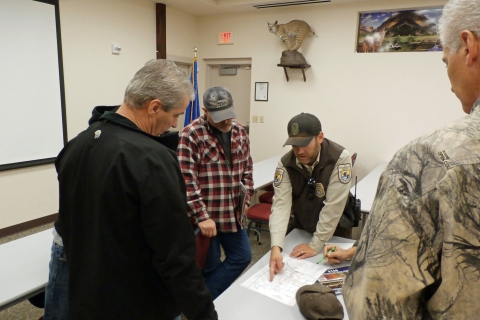 Law enforcement officer pointing to a map during a briefing