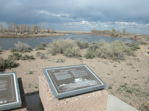 Plaques set in stone mark a historic site along a river.