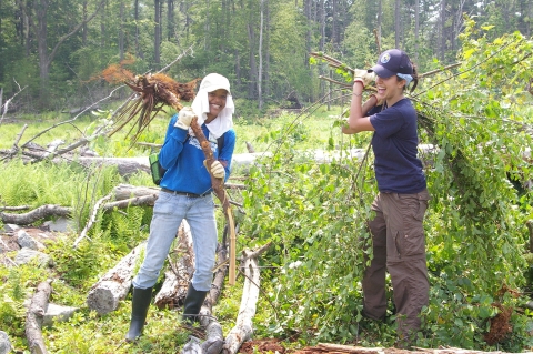 Two student volunteers holding invasive species.