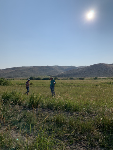 Two people inspect a fence at a livestock operation