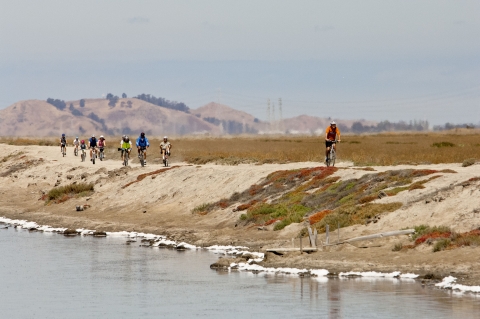Bikers take a trail along salt ponds.
