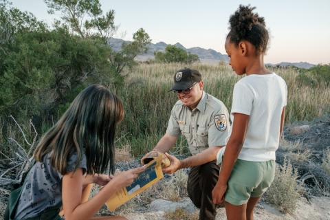 a ranger holds a tortoise shell and shows it to two girls