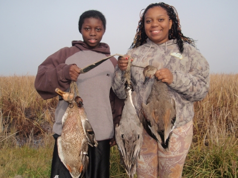 two junior hunters holding 3 ducks