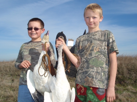 two junior hunters holding two snow geese