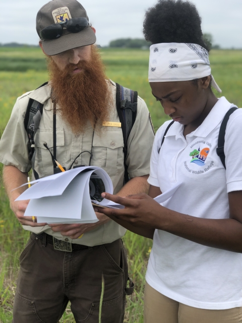 Biologist and and youth intern look through paper on a clipboard