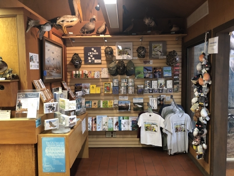 image of several books, various t shirts, stuffed animals, stuffed birds, postcards, notecards, and hats.