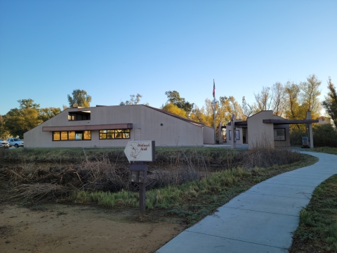 Pathway leading to Sacramento Refuge Visitor Center with trailhead sign that says "Wetland Walk"