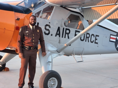 African American man stands in front of plane with "U.S. AIR FORCE" on side