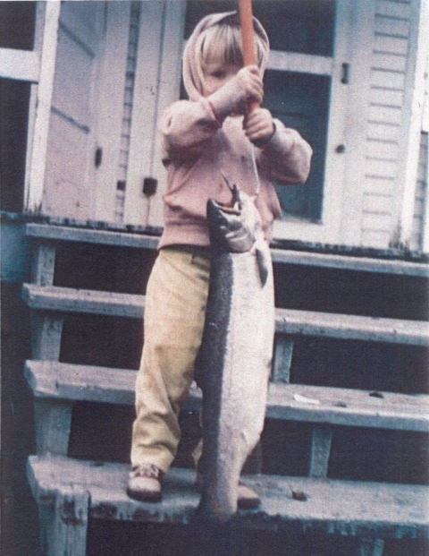 young child holding up large fish