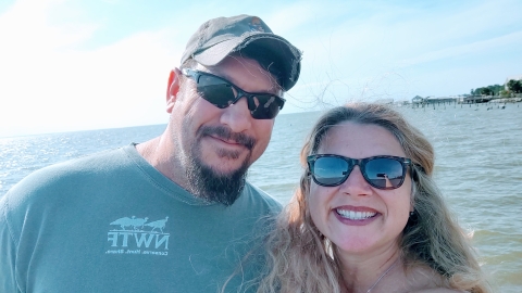 Carrie taking a selfie of her and Ronald with the ocean behind them.