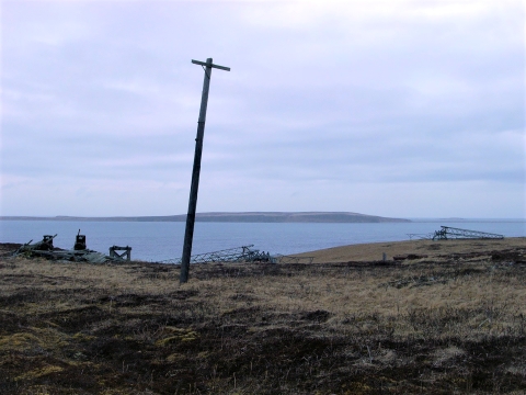 Abandoned equipment on an island: leaning electrical pole, fallen radio towers, and other debris.