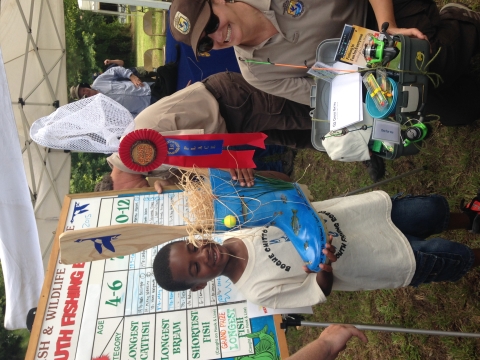 Boy holds grand prize boot as FWS employee holds some of the items he won