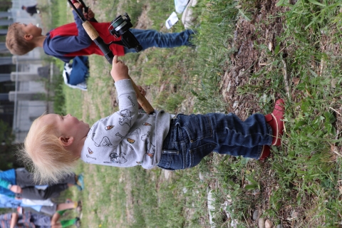An excited toddler holds a fishing pole.