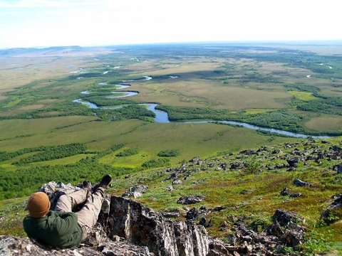 a person sitting on a hill looking down at a river valley