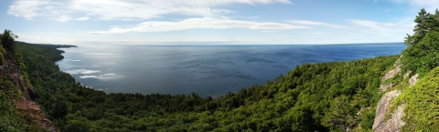 A rocky and wooded shoreline of a large lake.