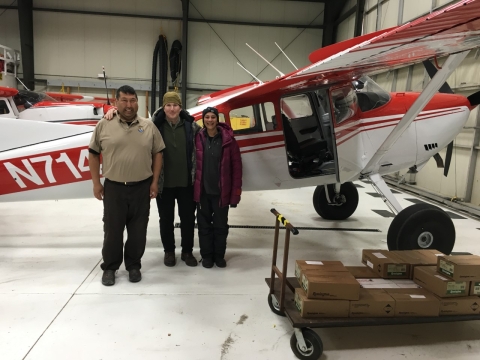 a woman by two men in an airplane hangar