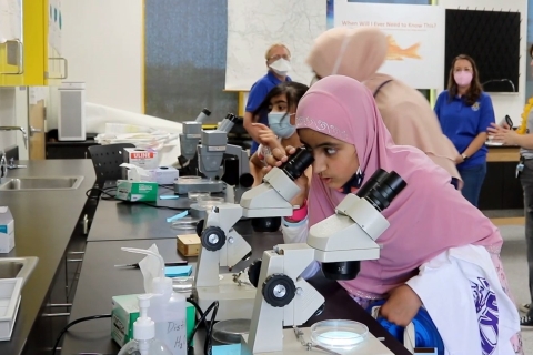 Two girls look into microscopes