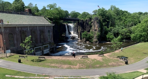 Paterson Great Falls and the Passaic River with nearby path and historic building.