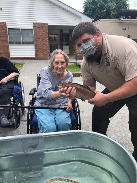 USFWS employee and woman in wheelchair holding a Rainbow trout and fishing pole