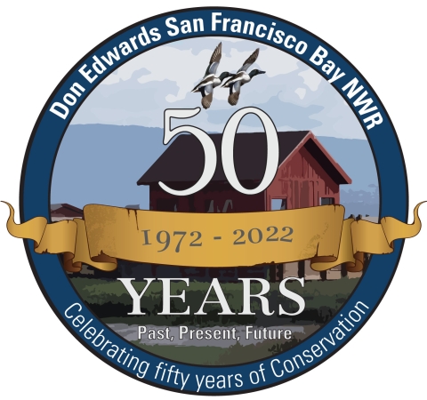 A logo for the 50th anniversary of Don Edwards San Francisco Bay National Wildlife Refuge. Circle text on top reads Don Edwards San Francisco Bay NWR. Text on the bottom reads, Celebrating fifty years of Conservation. Banner across the middle has the years 1972 - 2022. There is a large number fifty and text that reads Years, Past, Present, Future in the middle with an illustration of a wooden structure, blue skies