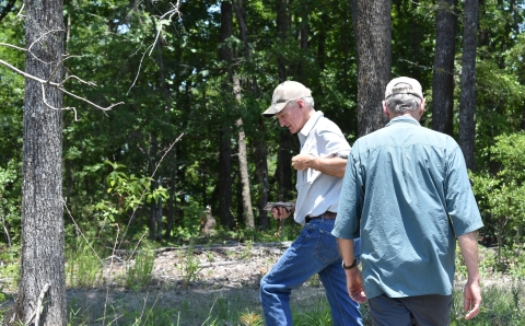 Two men with caps walk in the woods