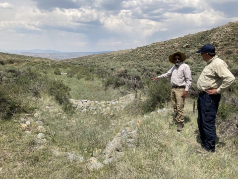 Two people observing rocks arranged in a large open field.
