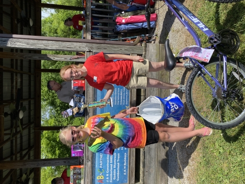 girl holding fish and woman giving her a trophy 