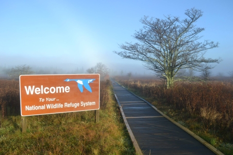 a welcome sign greets visitors near a boardwalk trail