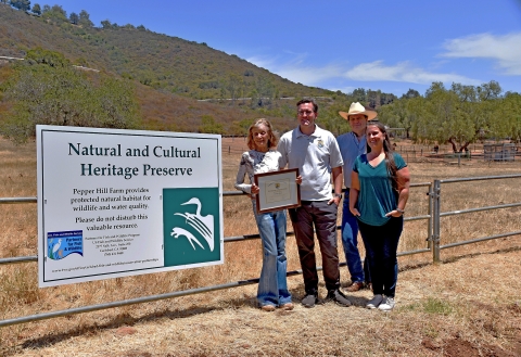 two men and two women stand next to a sign that reads Natural and Cultural Heritage Preserve
