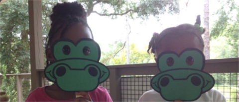 Two kids wearing alligator masks they made during an education program.