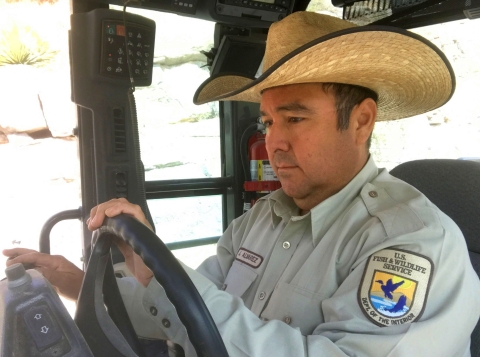 A man in a hat and a U.S. Fish and Wildlife Service uniform sitting in the cab of  a vehicle