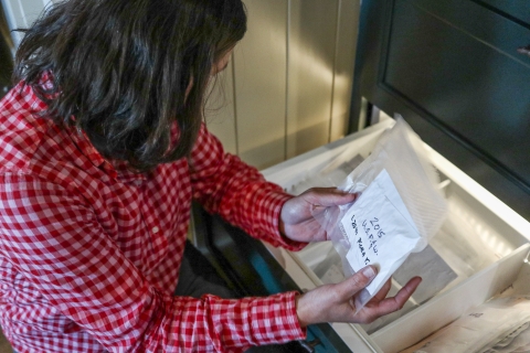 Person kneeling down holding a clear, plastic bag labeled "2015 U.S. F. & W."