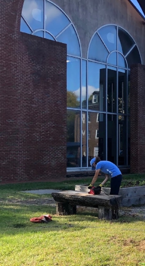 A person using a belt sander in a garden.