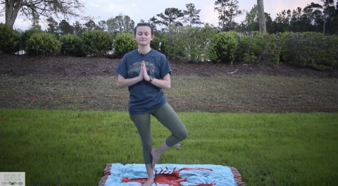 A young woman doing a yoga pose in a garden.