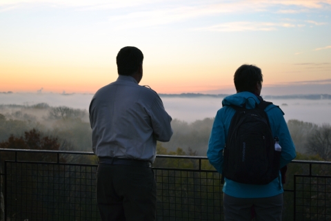 Two adults at an overlook view a misty landscape