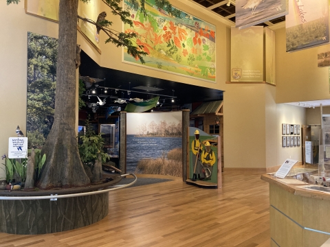 An open, well-lit atrium with an information desk and interpretive exhibits, including a diorama of a forest and a photo stand of wildland firefighters