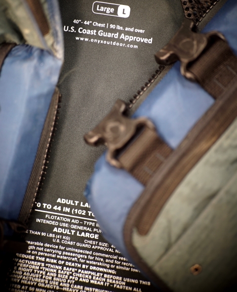 Close-up photo of a personal floatation device (life jacket) with buckles and the language inside of the item.