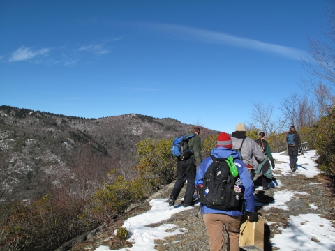 Group of people hiking a trail with a neighboring ridge in the background