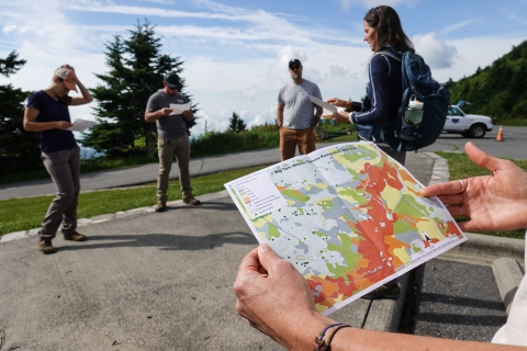 A group of people standing on a sidewalk holding maps