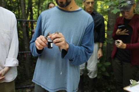 biologist holds a bird and a spool of bands 