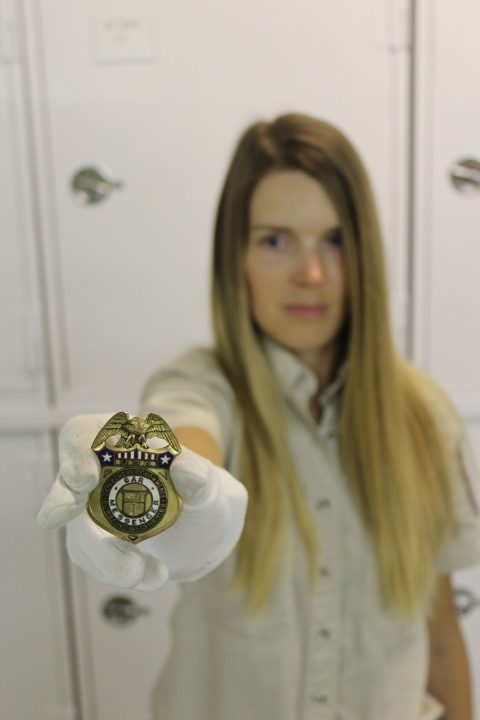 April poses with a Bureau of Fisheries badge from the archives