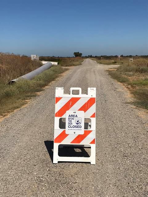 orange and yellow striped billboard with smaller sign that reads Area Beyond this Sign Closed