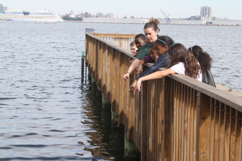 Children on a boardwalk point into the water