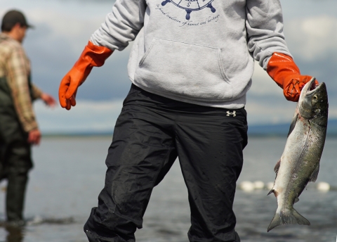 someone holding a salmon with a net in the background