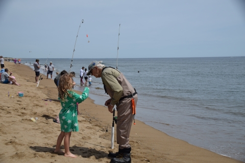 Volunteer surf caster instructs young child on the beach