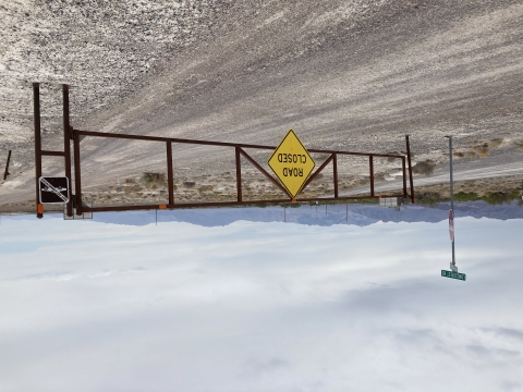 Dirt road with a closed gate, sign reads Road Closed. 