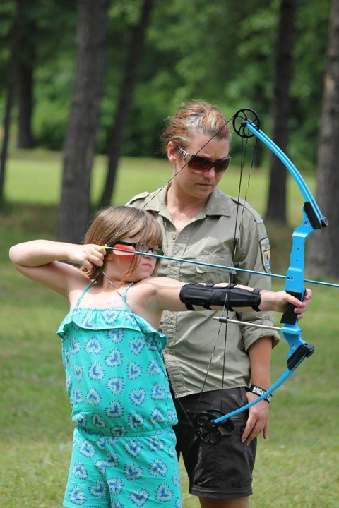 Sara works with a camper from Camp Quality AR as an archery instructor