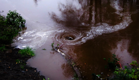 A whirlpool caused by a too-small culvert that has to deal with too much water flow.