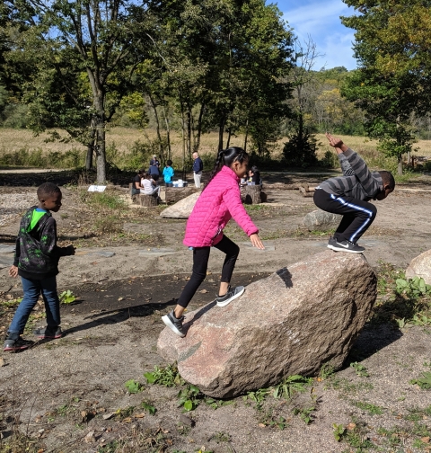 Children jumping off rock while playing