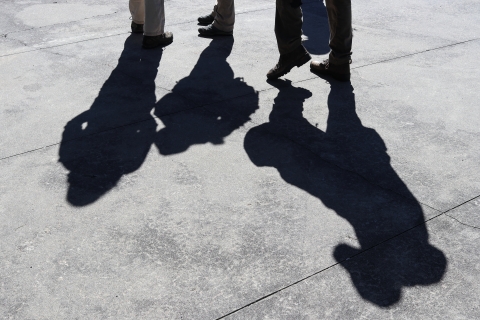 Shadows of four people standing on a paved surface